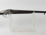 un fusil posé sur un socle transparent, devant un fond blanc