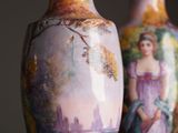 two vases with paintings on them sitting on a table