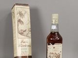 two bottles of rum in front of a cardboard box and a bottle of rum