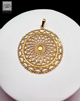 une assiette blanche sur laquelle est posé un pendentif en or