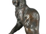 bronze statue of a cat sitting on a rock on a white background