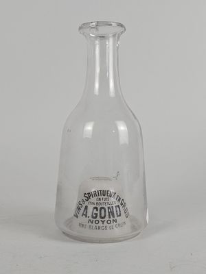 une vieille bouteille en verre avec une étiquette, posée sur une table