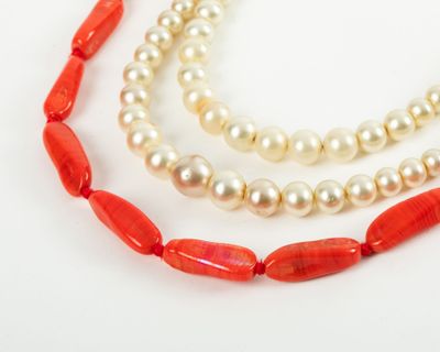 two strands of red coral and white pearls on a white surface