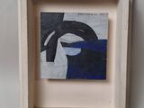 painting of a woman ' s face in a white frame on a white wall