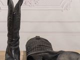 pair of black boots and a hat sitting on top of a wooden table