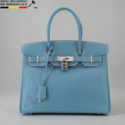 un sac à main en cuir bleu muni d'un fermoir métallique sur la poignée