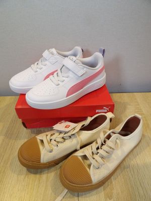white and pink puma sneakers on top of a box on a wooden table