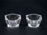 two clear glass candlestick holders on a black background