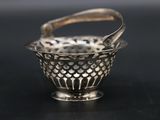 an antique silver basket with a handle on a black surface