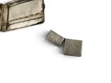 two pieces of silver on a white surface