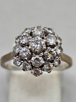 un gros plan d'une bague sertie de diamants en grappe sur une surface blanche