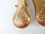 two gold shoes that are sitting on a white surface