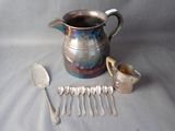 a silver pitcher with spoons and spoons next to it