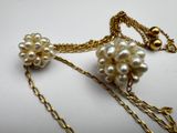 a close up of a necklace with pearls and chains on a white surface