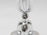 a silver figurine of a cat sitting on top of a table
