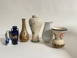 five different vases sitting on a white surface