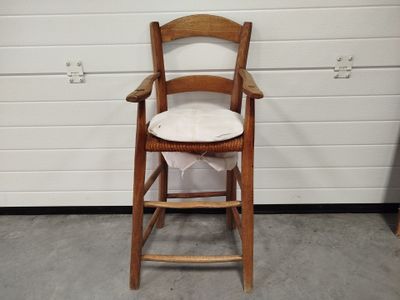 une chaise en bois avec un coussin, posée devant un mur blanc