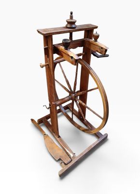 an old spinning machine with wooden wheels on a white surface