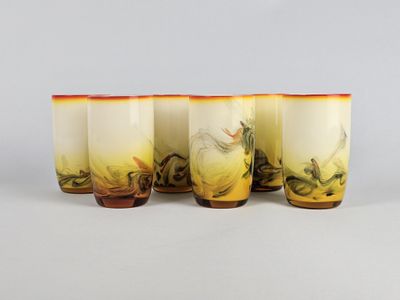 quatre verres ornés de motifs jaunes et orange sont alignés sur une surface blanche