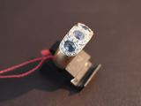 a gold ring with a blue stone and a red string