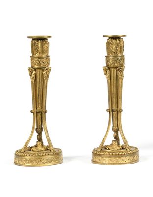 pair of antique brass candlesticks on pedestals on a white background