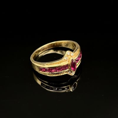 un gros plan d'une bague en or sertie de pierres roses sur un fond noir