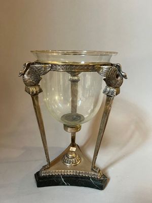 a silver vase with two birds on it on a stand