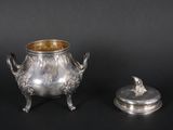 two silverplated objects on a black surface with a black background