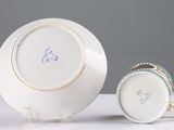 a white plate with a gold rim and a blue and white cup