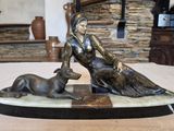 une statue représentant une femme et un chien assis sur une table