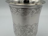 an antique silver cup with a floral design on the rim