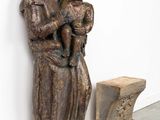 statue of a woman holding a child in her arms next to a bench