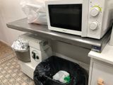 a microwave sitting on top of a counter next to a trash bag