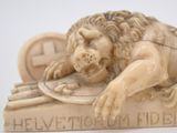 sculpture of a lion laying on top of a book on a white surface