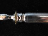 a silver knife with a gold handle on a black surface