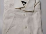 La chemise est blanche et possède un col boutonné.