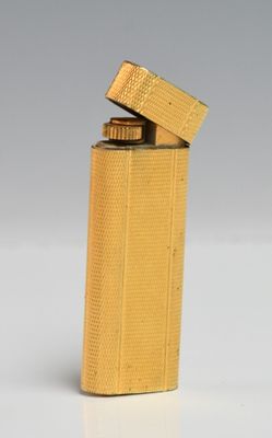 a gold lighter sitting on top of a table next to a white background
