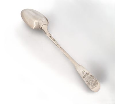 une cuillère en argent avec un manche de cuillère sur une surface blanche