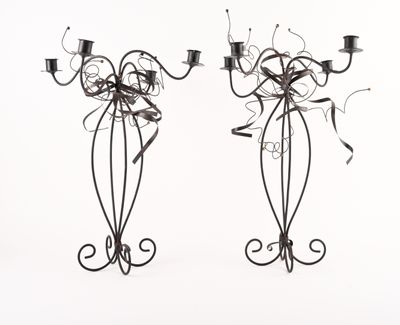 deux chandeliers en métal sur lesquels sont posées des bougies, posés sur une surface blanche