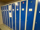 Plusieurs casiers bleus sont alignés en rang dans un couloir