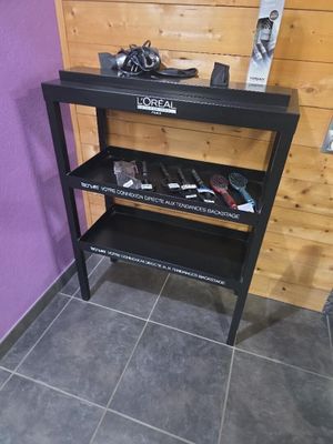 une étagère noire sur laquelle sont posés des outils, dans un coin de la pièce