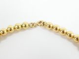 a gold beaded necklace with a gold clasp