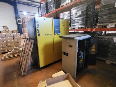 a refrigerator in a warehouse with boxes and pallets in the background