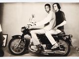 deux hommes assis sur une moto, posant pour une photo