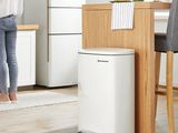 a woman standing at a kitchen table in front of a white air purifier