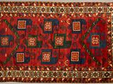 a close up of a red and blue rug on a white surface