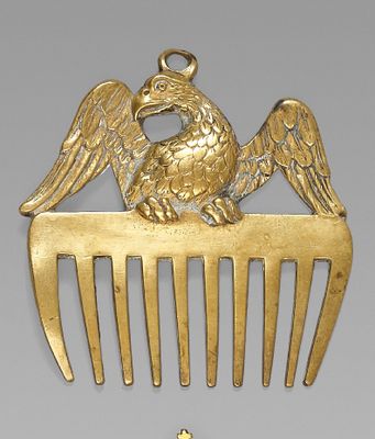peigne plaqué or orné d'un oiseau au sommet et d'une croix sur le côté