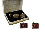 two cufflinks in a box with a red and black design