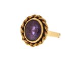 gros plan d'une bague en or avec une pierre violette