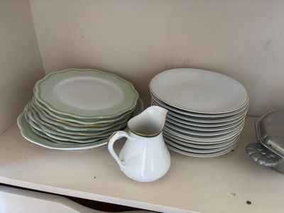 Plusieurs assiettes et tasses sont empilées sur une étagère dans une cuisine